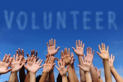 photo of people hands with the word volunteer above them