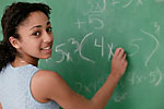 girl writing on chalk board in math class